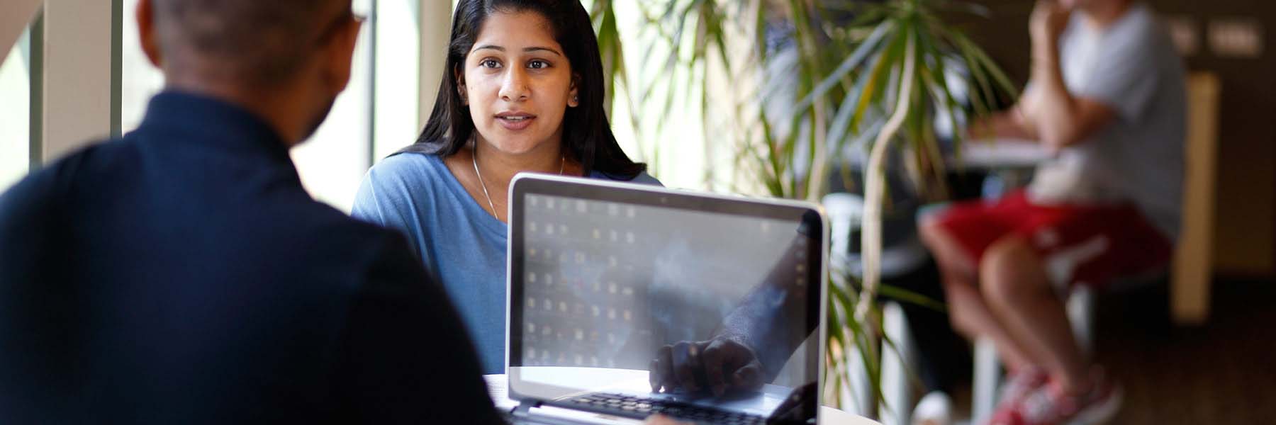 Two people speak over a laptop.